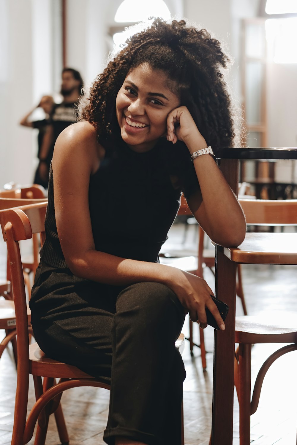 woman in black tank top and gray pants sitting on brown wooden chair