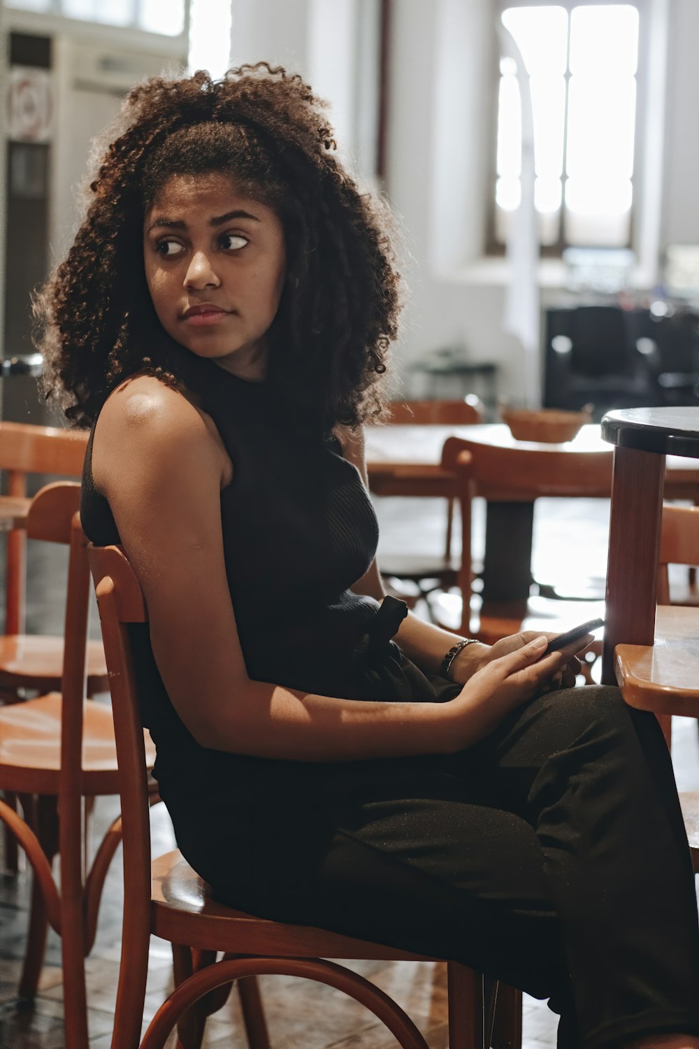 woman in black tank top and gray pants sitting on brown wooden chair