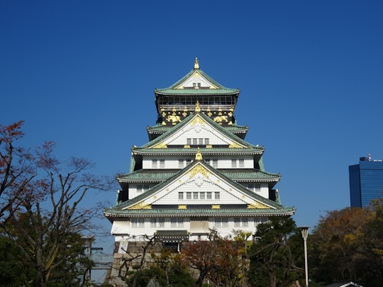 white and blue concrete building under blue sky during daytime in Osaka Castle Park Japan