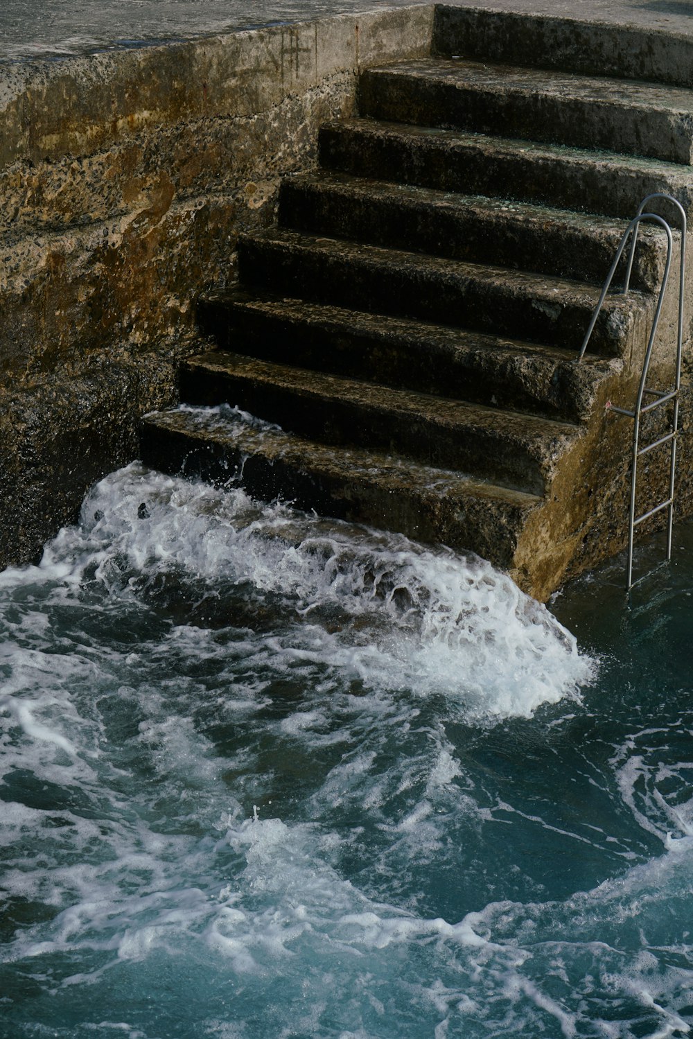 water waves hitting the concrete stairs