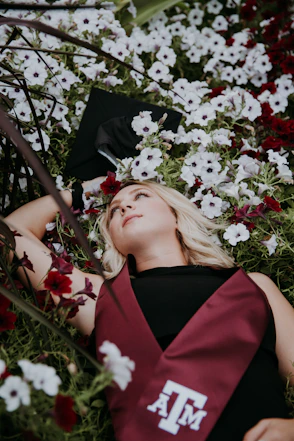 woman in black and red sleeveless dress lying on white and pink flowers