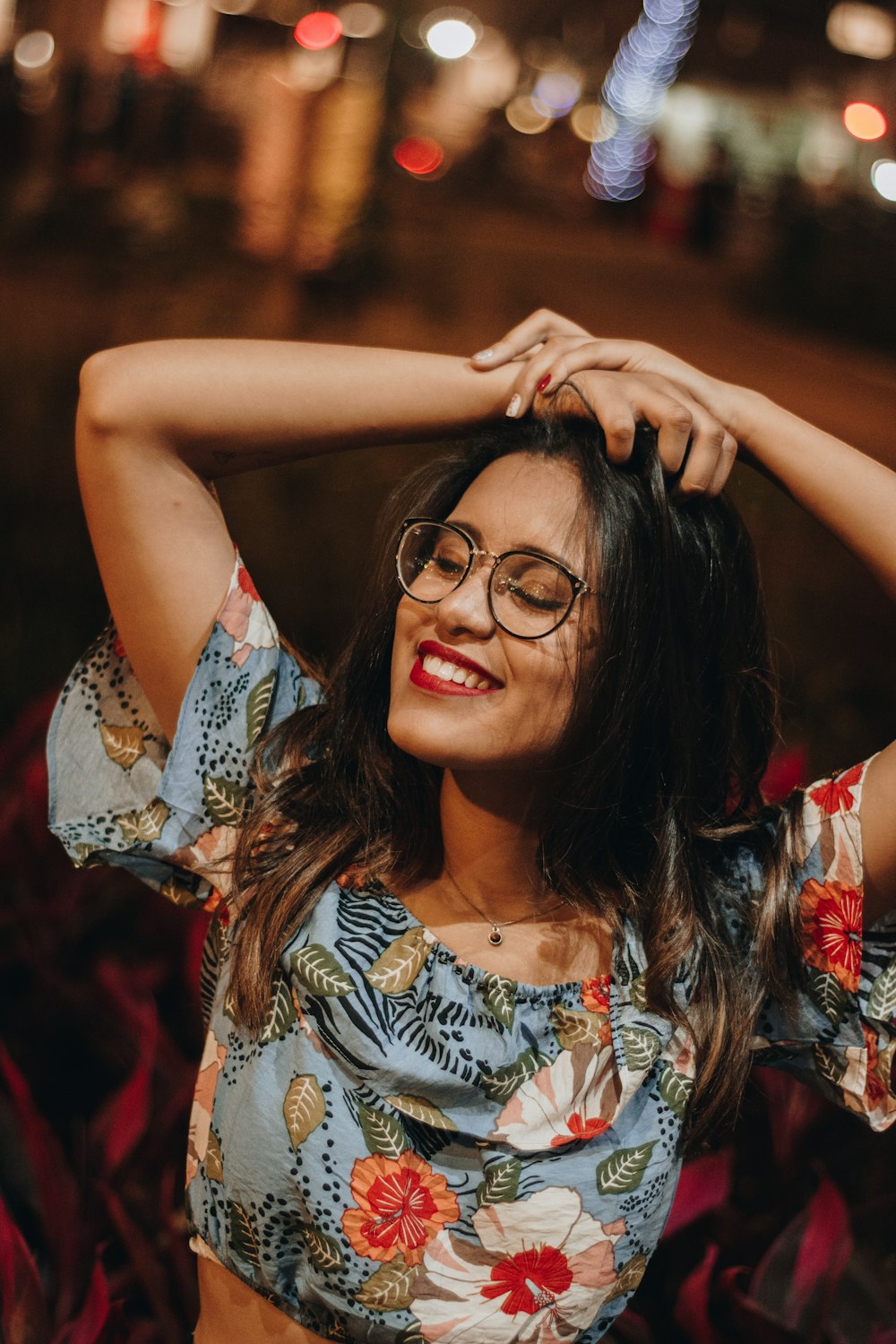 woman in white red and blue floral sleeveless top wearing black framed eyeglasses