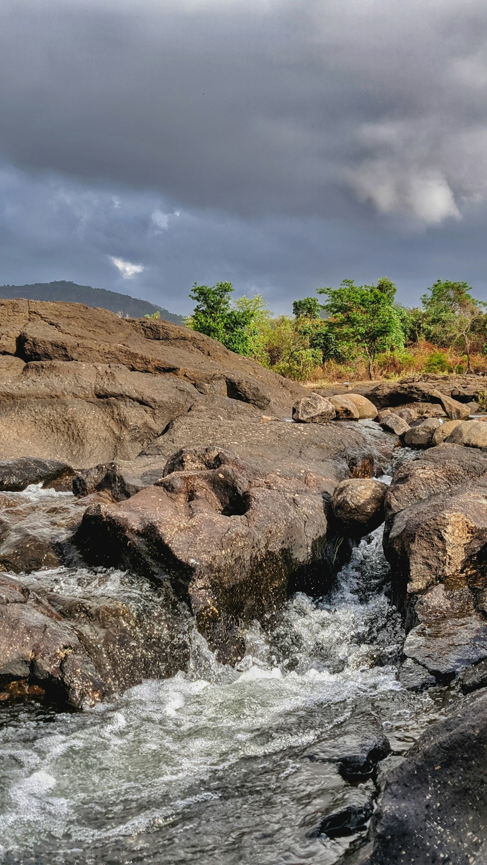 brown rocky mountain with green trees and river