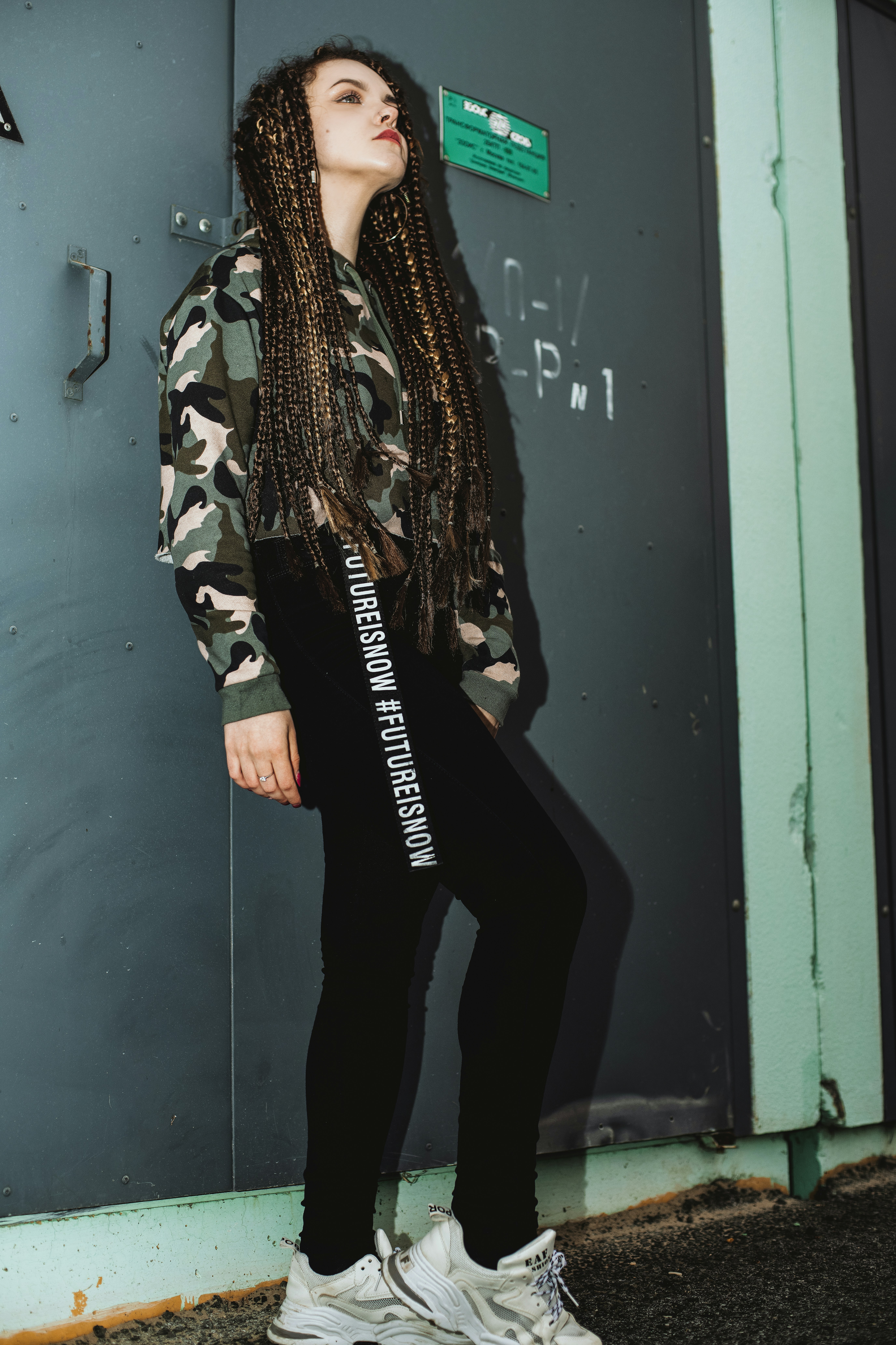 woman in black pants and black and white jacket standing beside blue wooden door