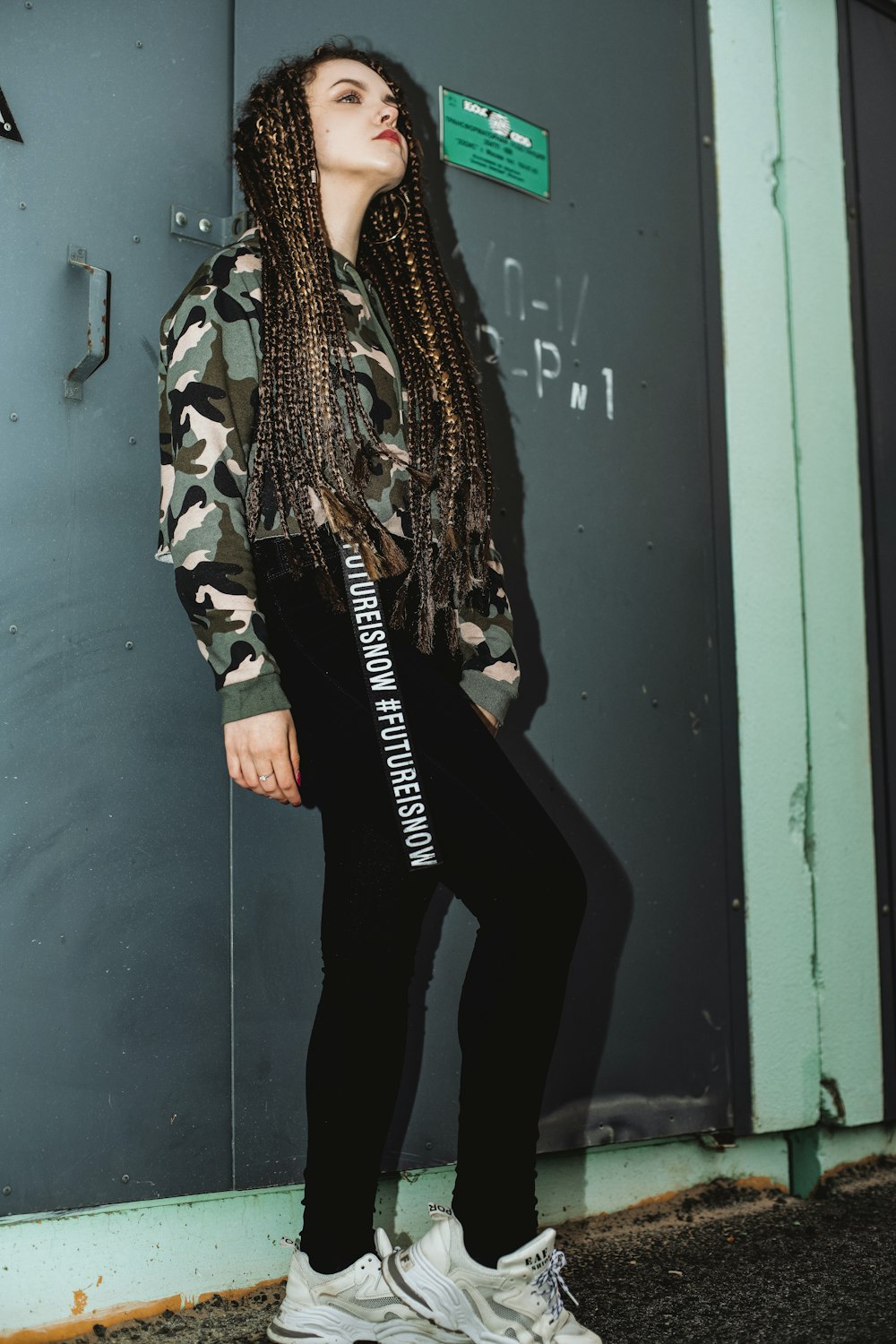 woman in black pants and black and white jacket standing beside blue wooden door