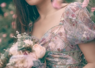 woman in white and pink floral dress holding white flowers