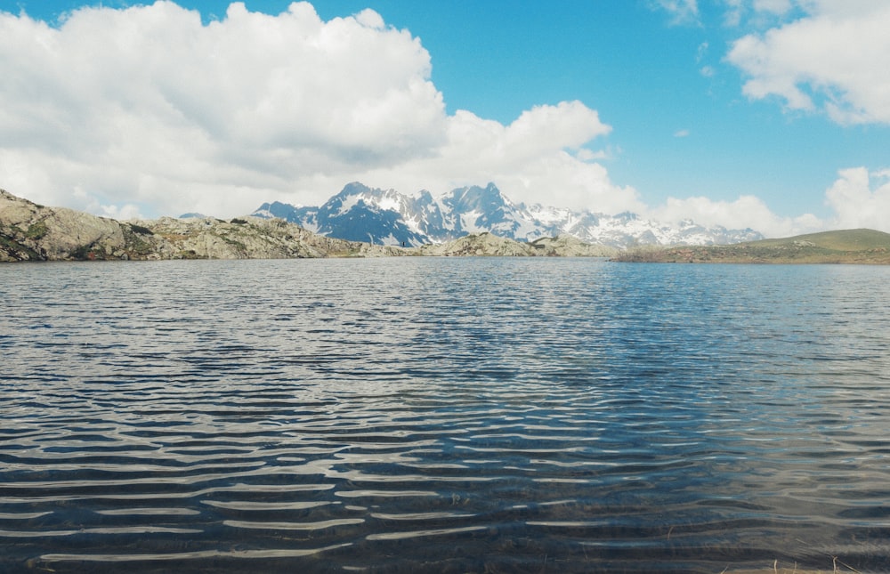 Montagna bianca e marrone vicino allo specchio d'acqua sotto il cielo blu durante il giorno
