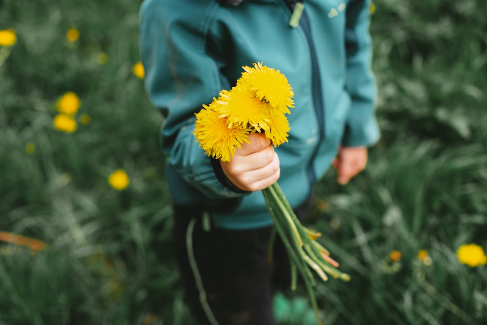 Persona in giacca blu che tiene il fiore giallo