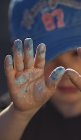 person in blue and white shirt covering face with hands