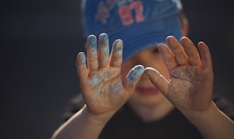 person in blue and white shirt covering face with hands