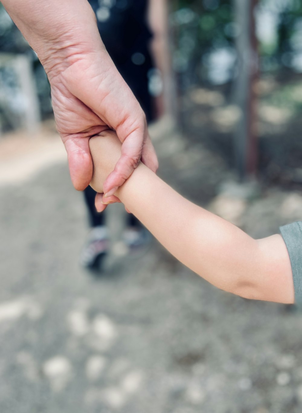 personne en chemise à manches longues grise tenant la main de bébé