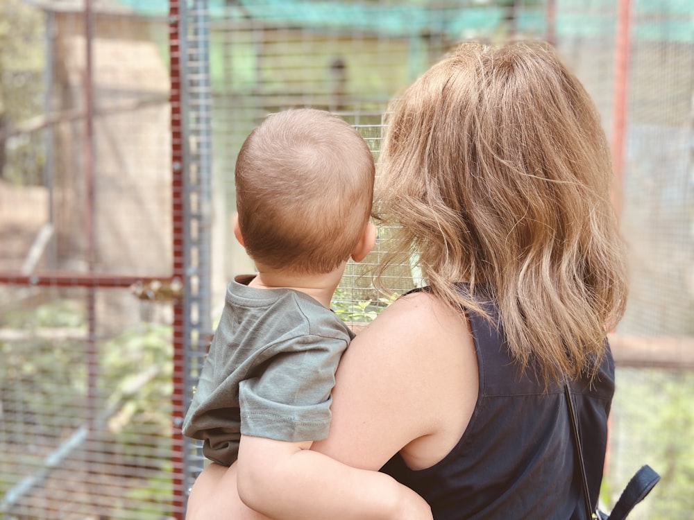 woman in black tank top carrying child in gray denim jacket