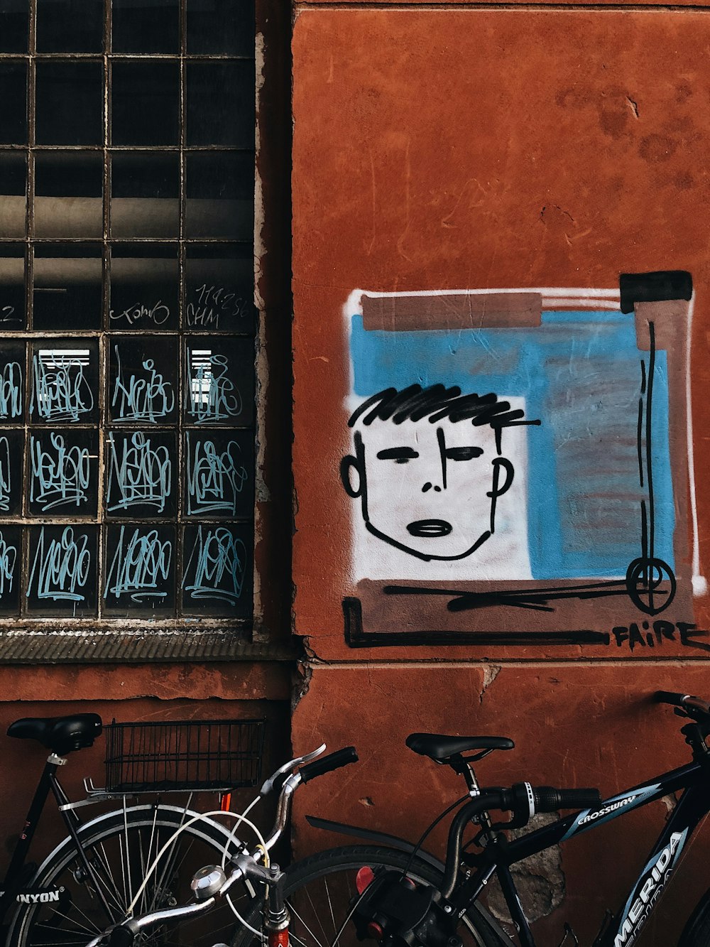 black bicycle beside blue wall with graffiti