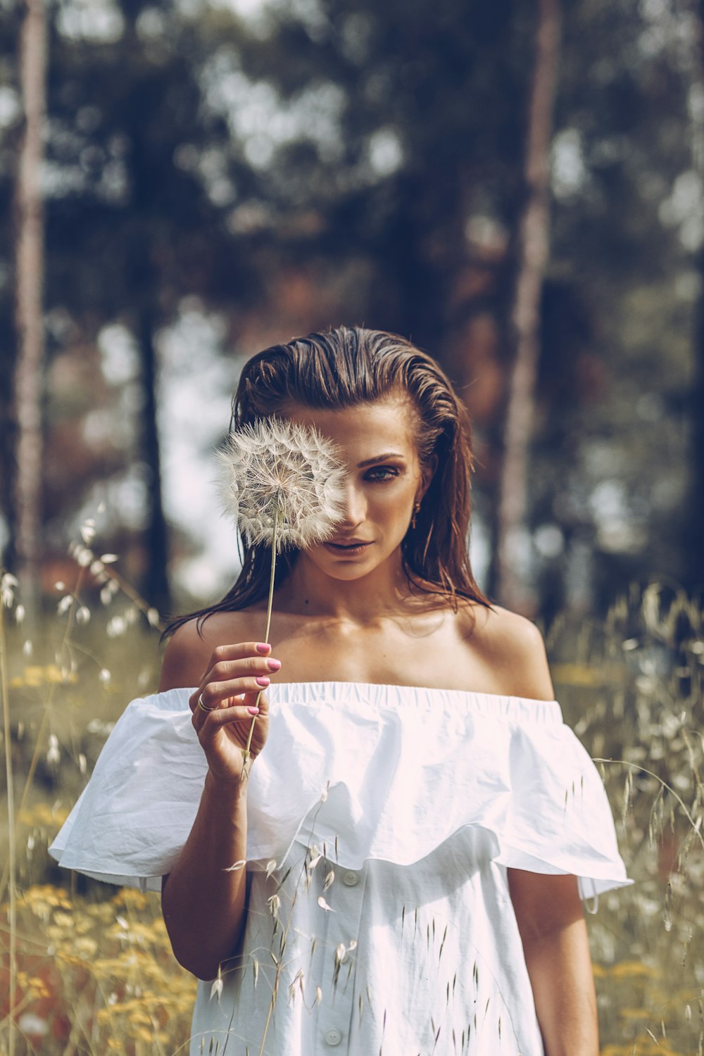woman in white off shoulder dress holding dandelion flower