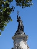 statue of man holding book under blue sky during daytime