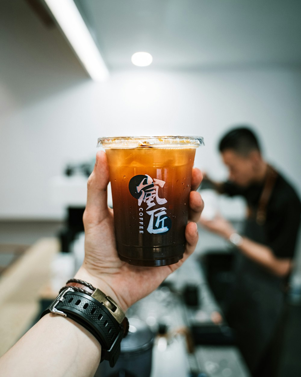 person holding clear drinking glass with brown liquid