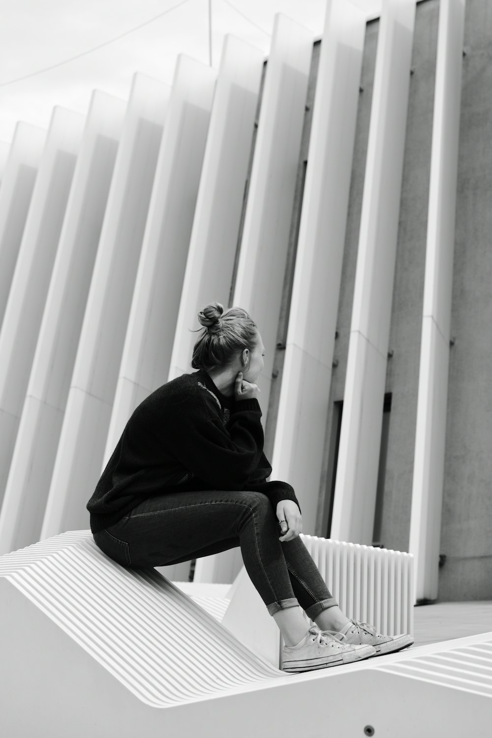 grayscale photo of woman in black long sleeve shirt and black pants sitting on stairs