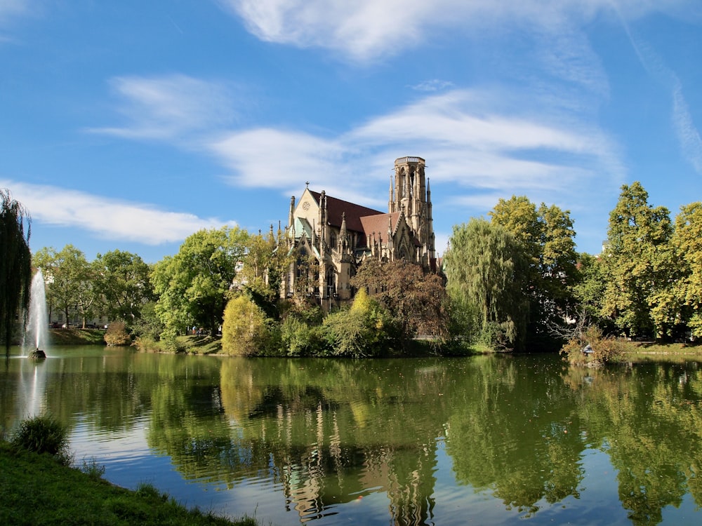 edificio in cemento marrone accanto agli alberi verdi e allo specchio d'acqua durante il giorno