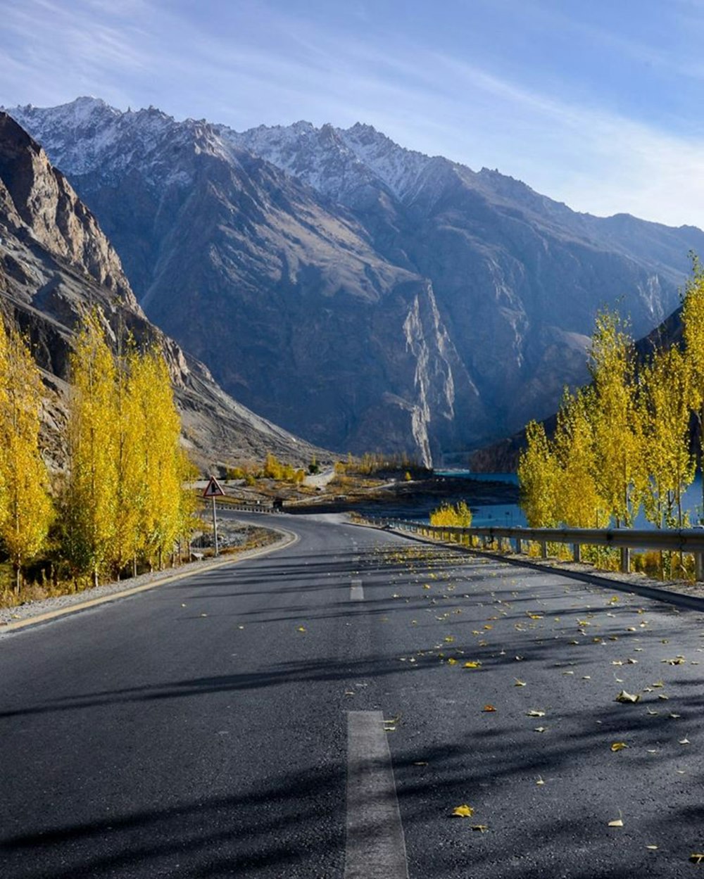 gray concrete road between green trees and brown mountains during daytime