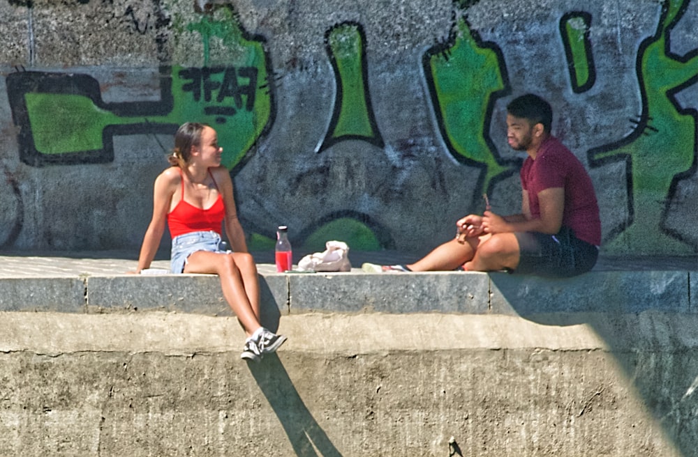 woman in red bikini sitting on concrete bench beside pool during daytime