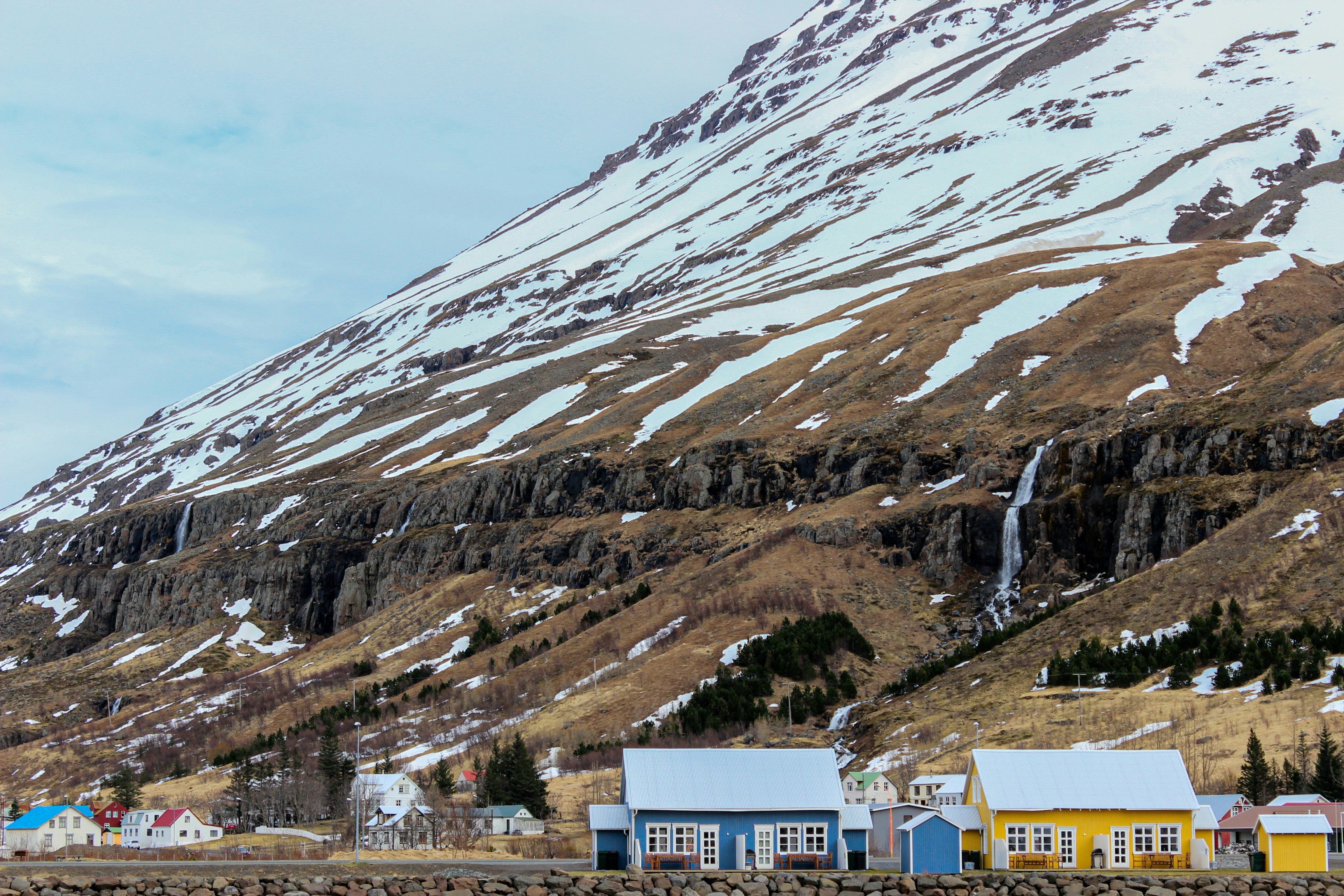 white and brown concrete buildings near snow covered mountain during daytime