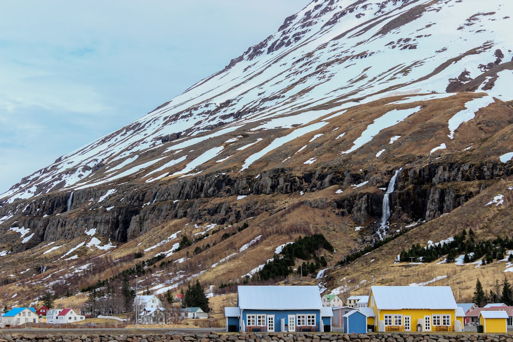 white and brown concrete buildings near snow covered mountain during daytime