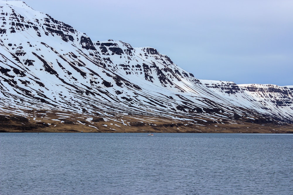 snow covered mountain near body of water during daytime