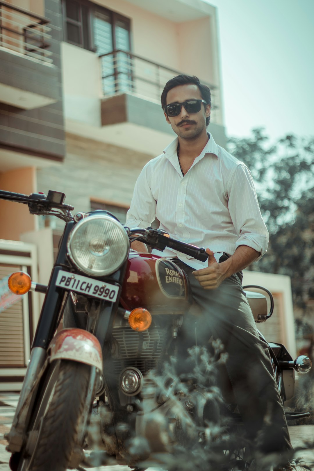 man in white dress shirt and black sunglasses standing beside black motorcycle during daytime