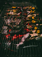 A group of friends enjoying a seaside BBQ with sizzling seafood on the grill