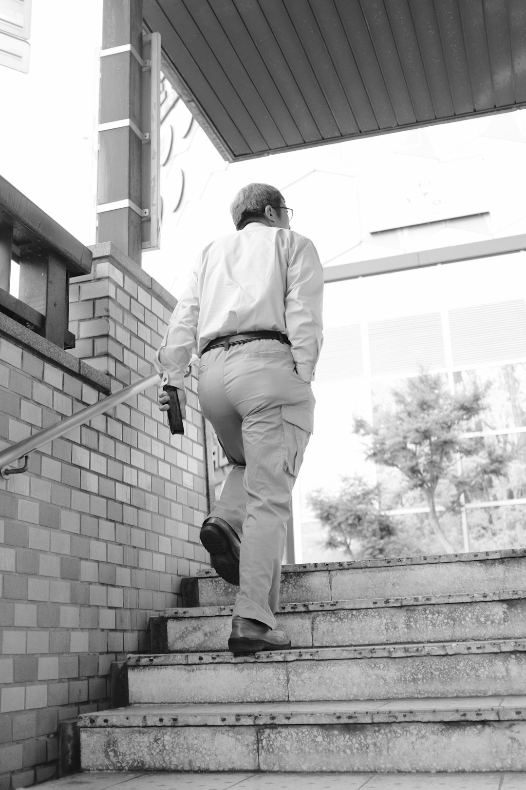 man in white dress shirt and brown pants sitting on concrete stair