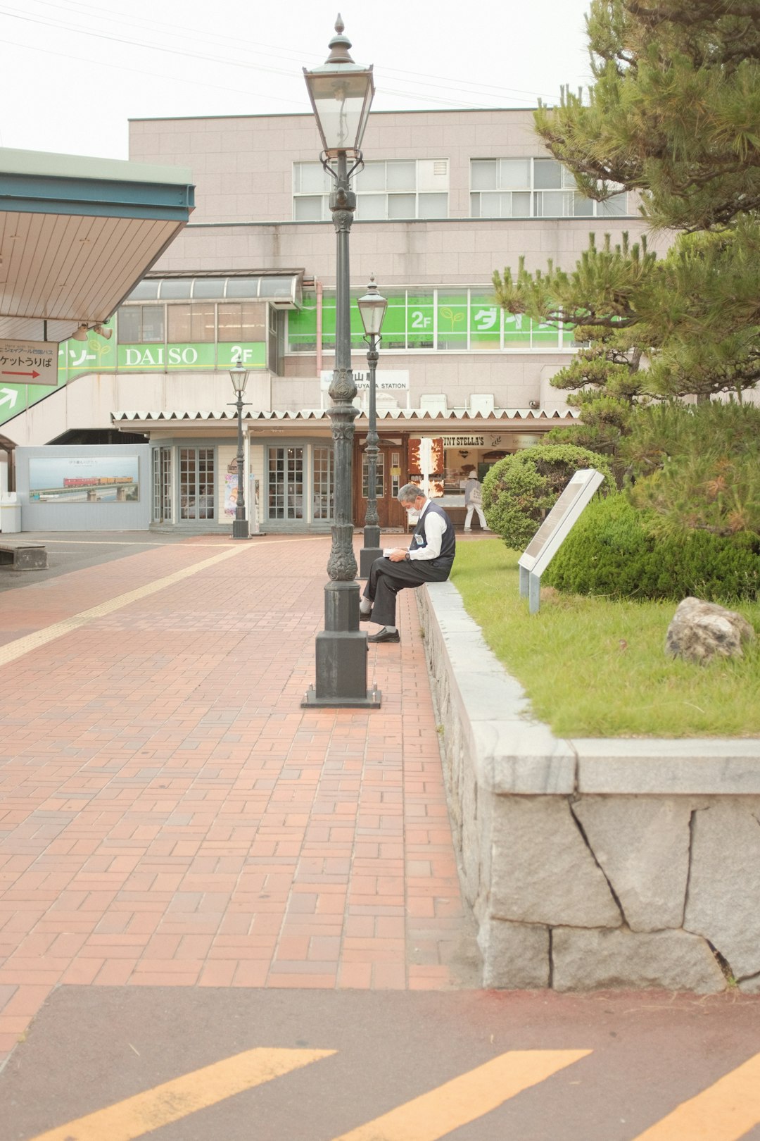 man in white shirt sitting on bench near road during daytime