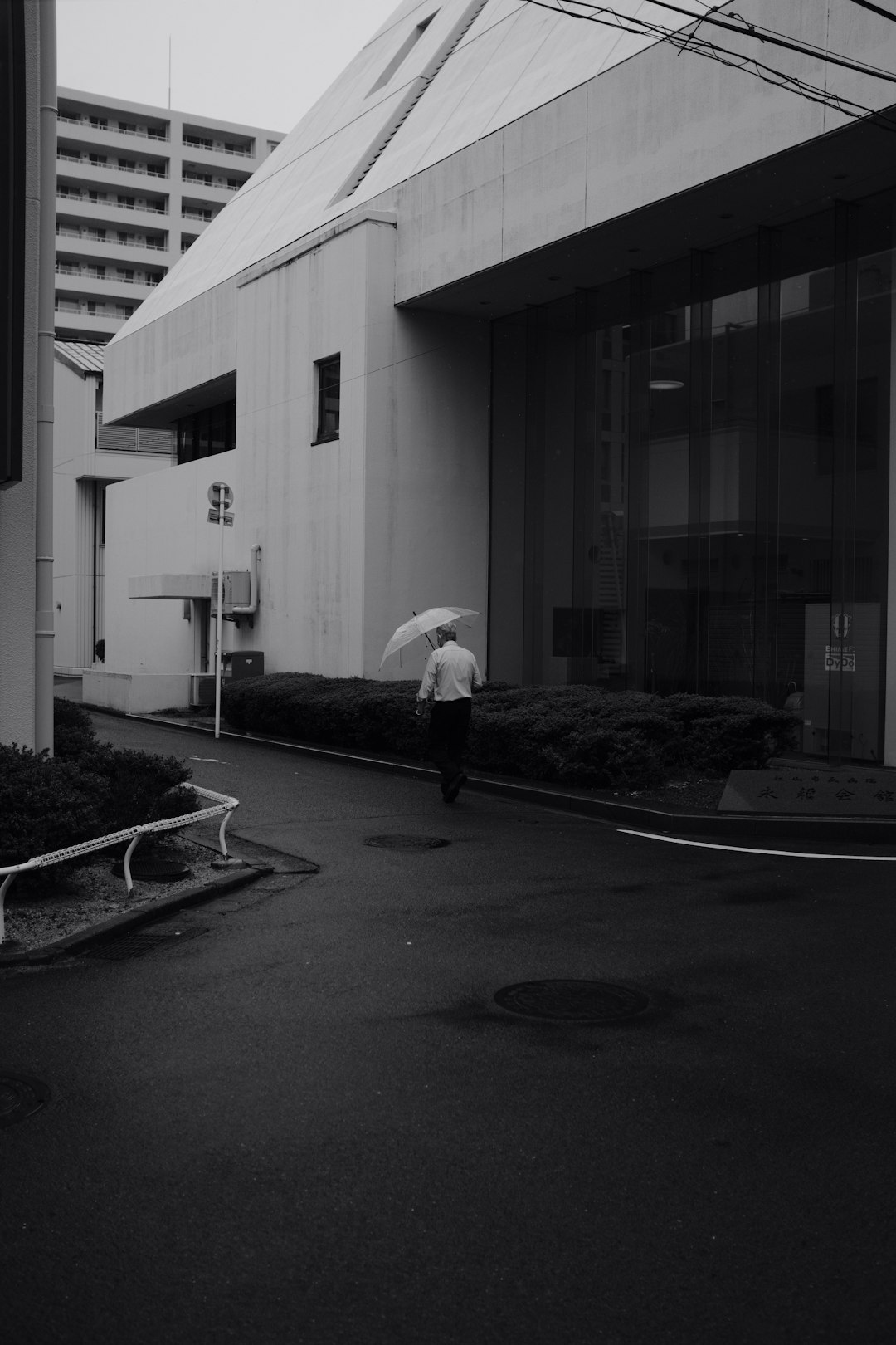 grayscale photo of person holding umbrella walking on street