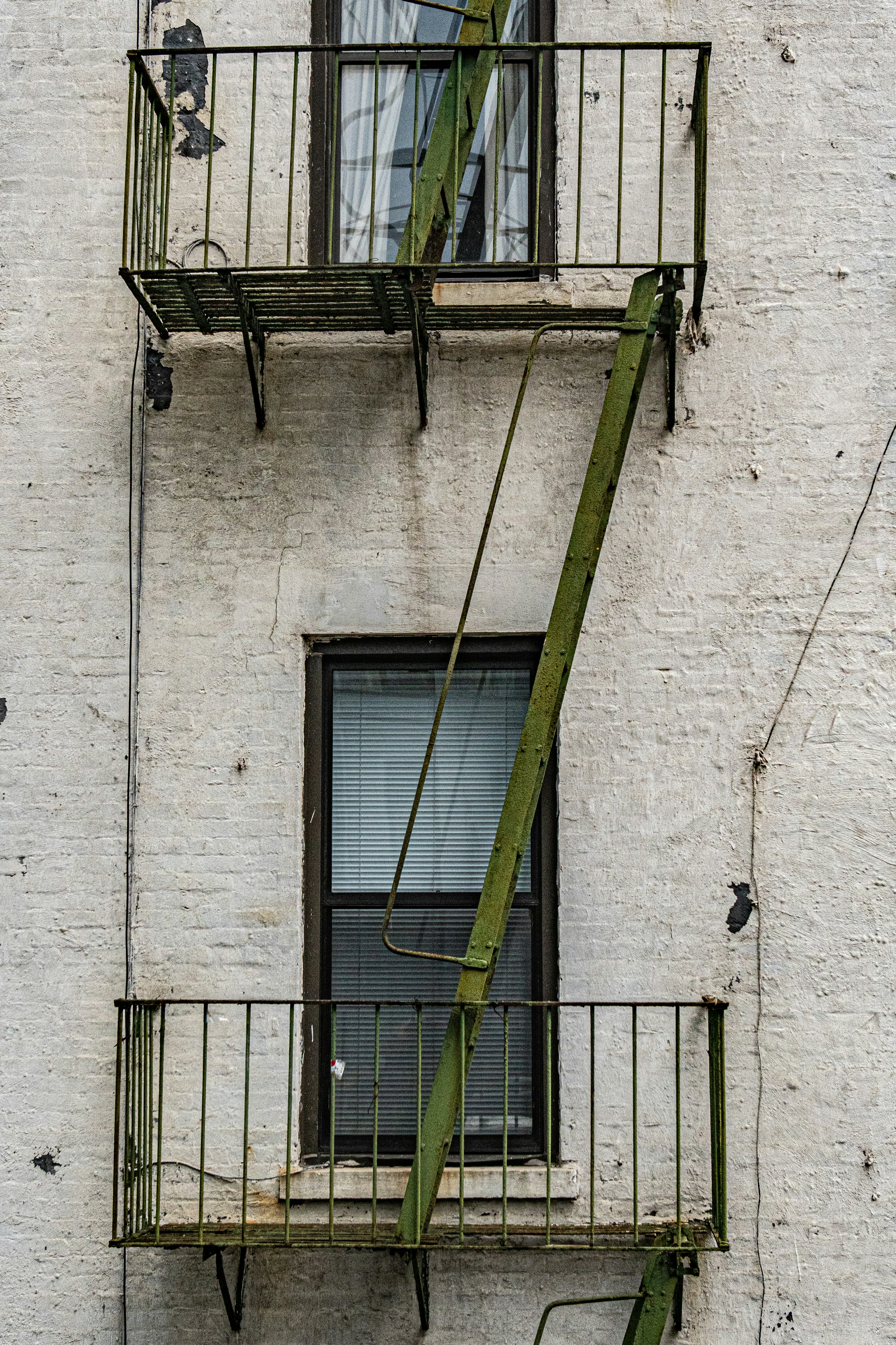 green metal ladder on white concrete wall