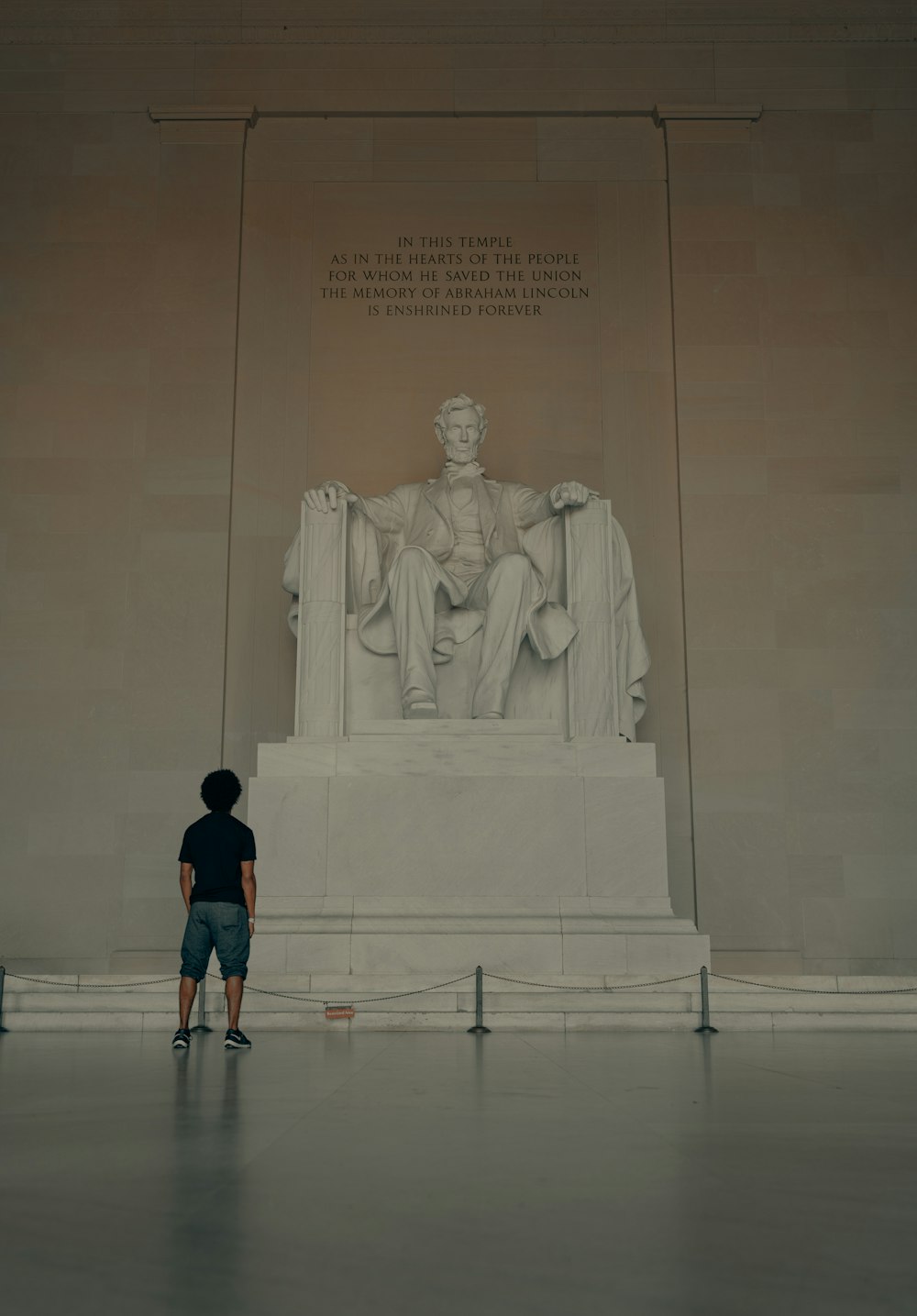 homem na camiseta preta em pé na frente da estátua