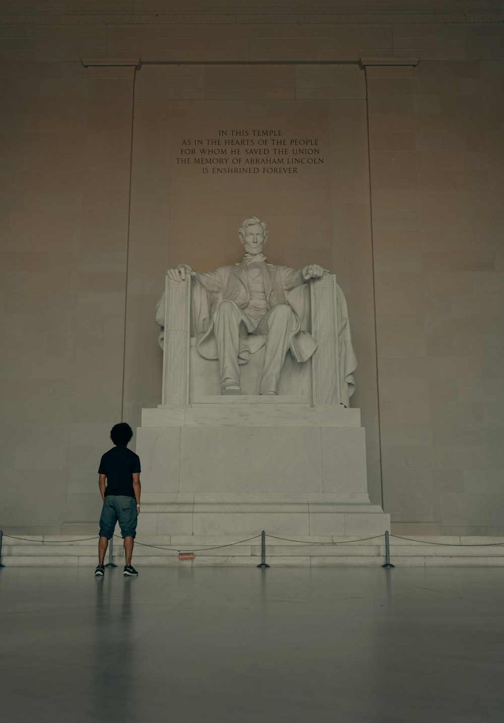 man in black t-shirt standing in front of statue