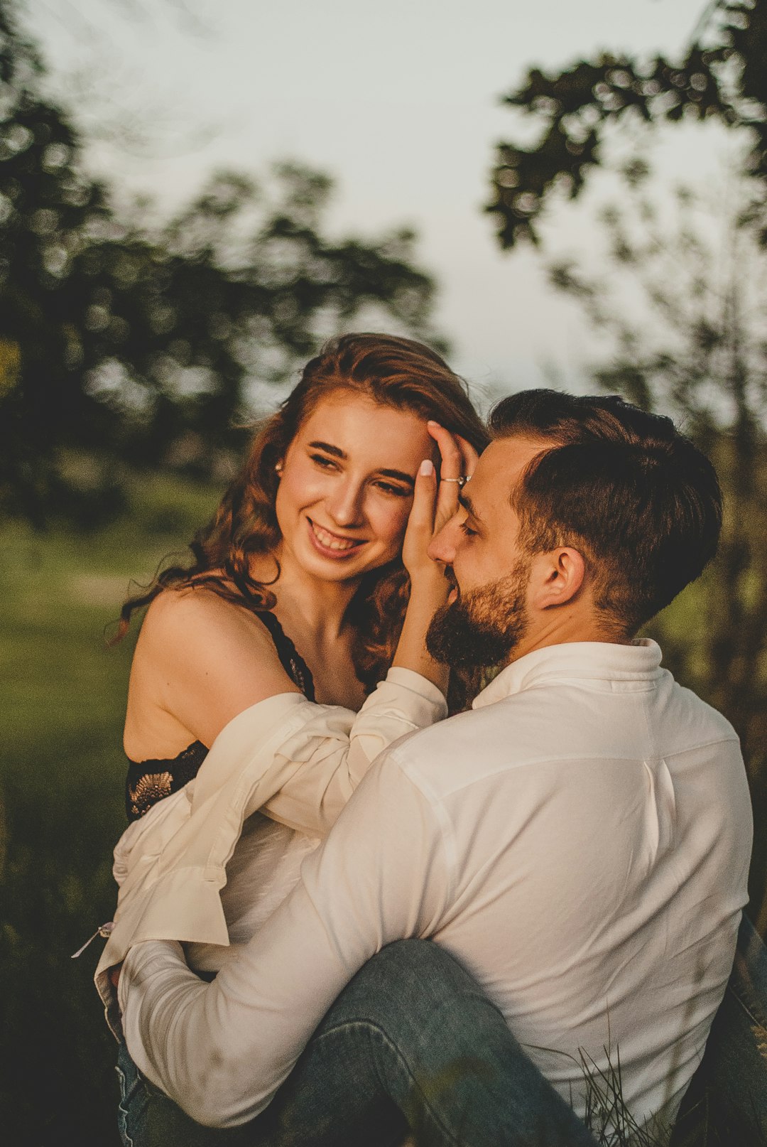 man in white dress shirt kissing woman in black and white floral sleeveless dress