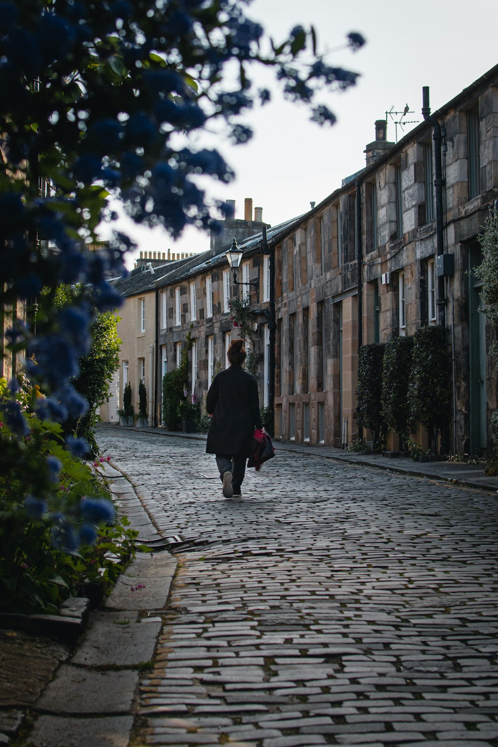 person in black coat walking on sidewalk during daytime