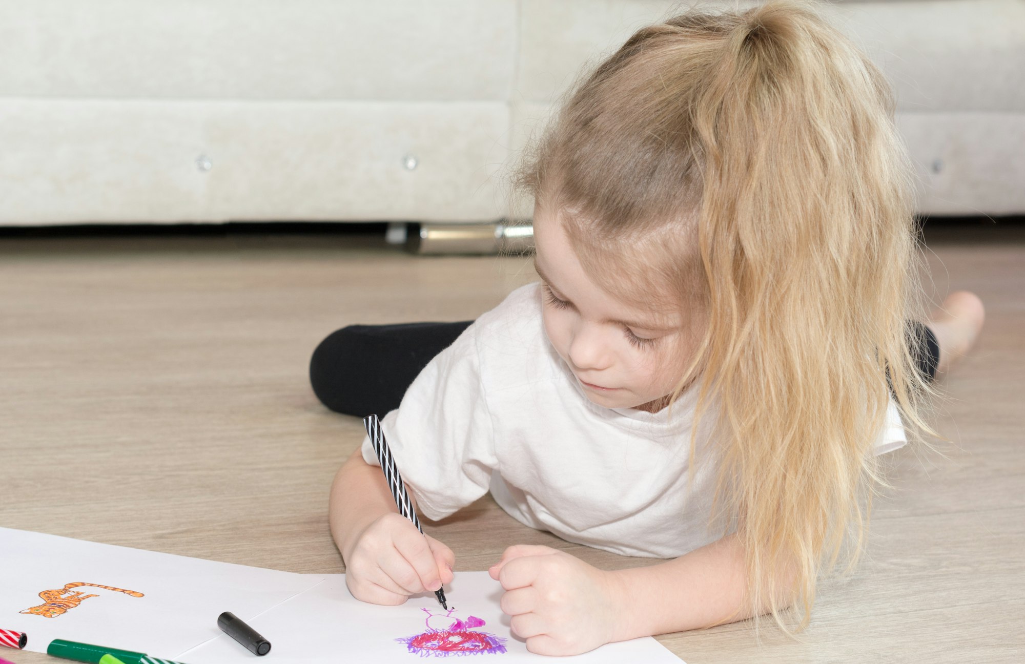 Little girl drawing coloring picture with pencils cute child daughter play laying on warm floor at home