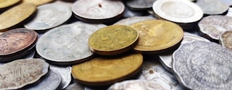 A close-up photo of vintage Indian coins spread out on a wooden table.