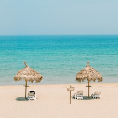 brown wooden beach lounge chairs on beach during daytime