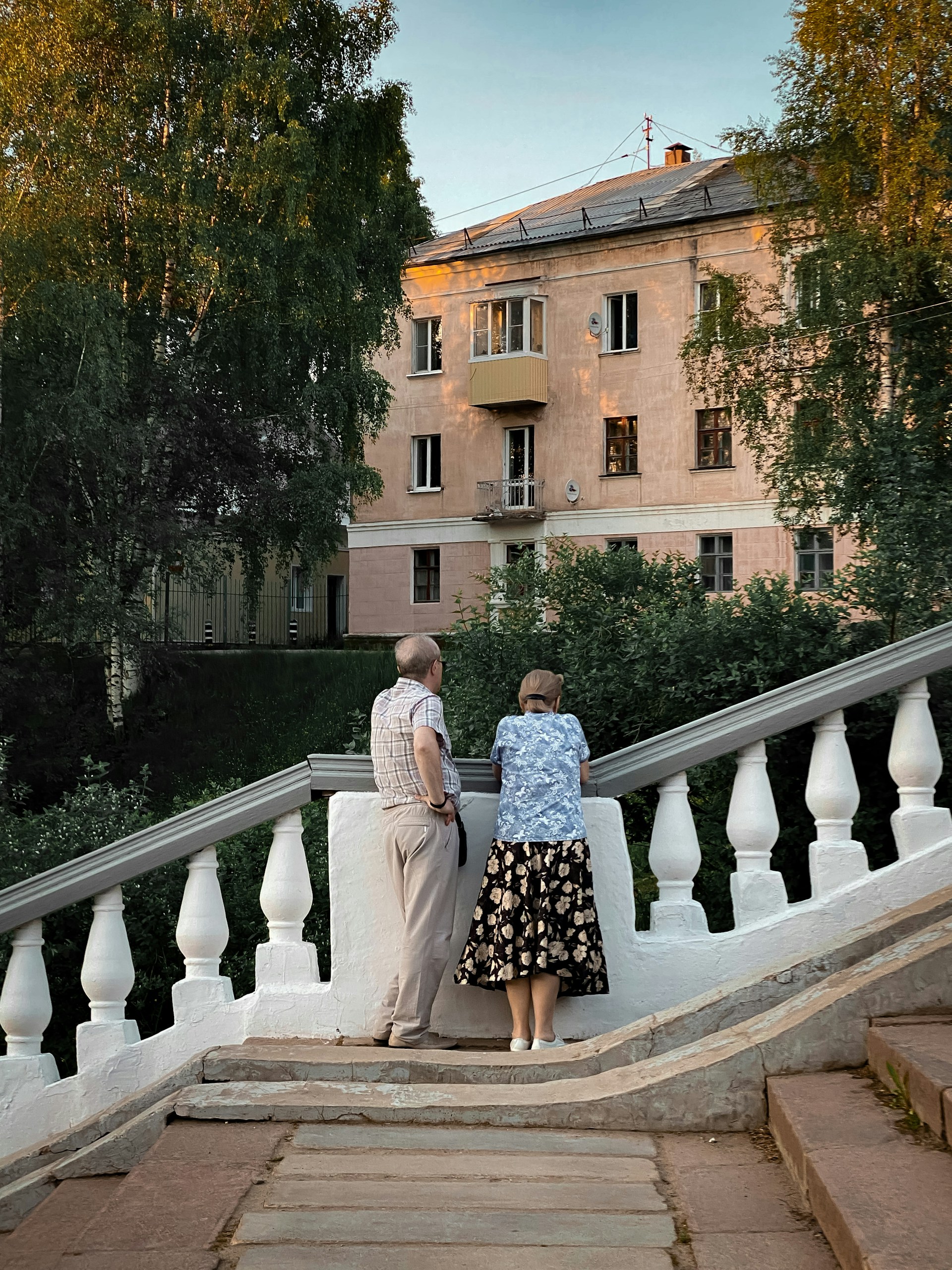 Elegant older couple enjoying a serene afternoon on their private terrace, with a Blue Oyster Concierge staff member discreetly attending to their needs.