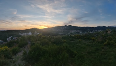 A scenic view of lush green fields and the village landscape at sunset.