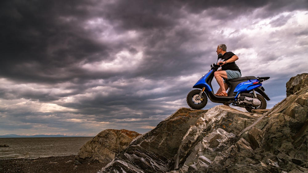 man in red shirt and blue denim jeans sitting on black and white motorcycle on gray