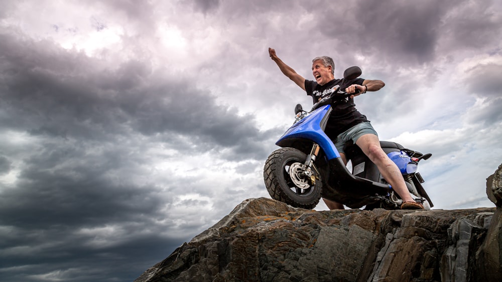 homme en veste noire et jean bleu chevauchant une moto bleue et blanche