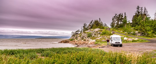 person standing on brown rock near green grass field during daytime in Kamouraska Canada