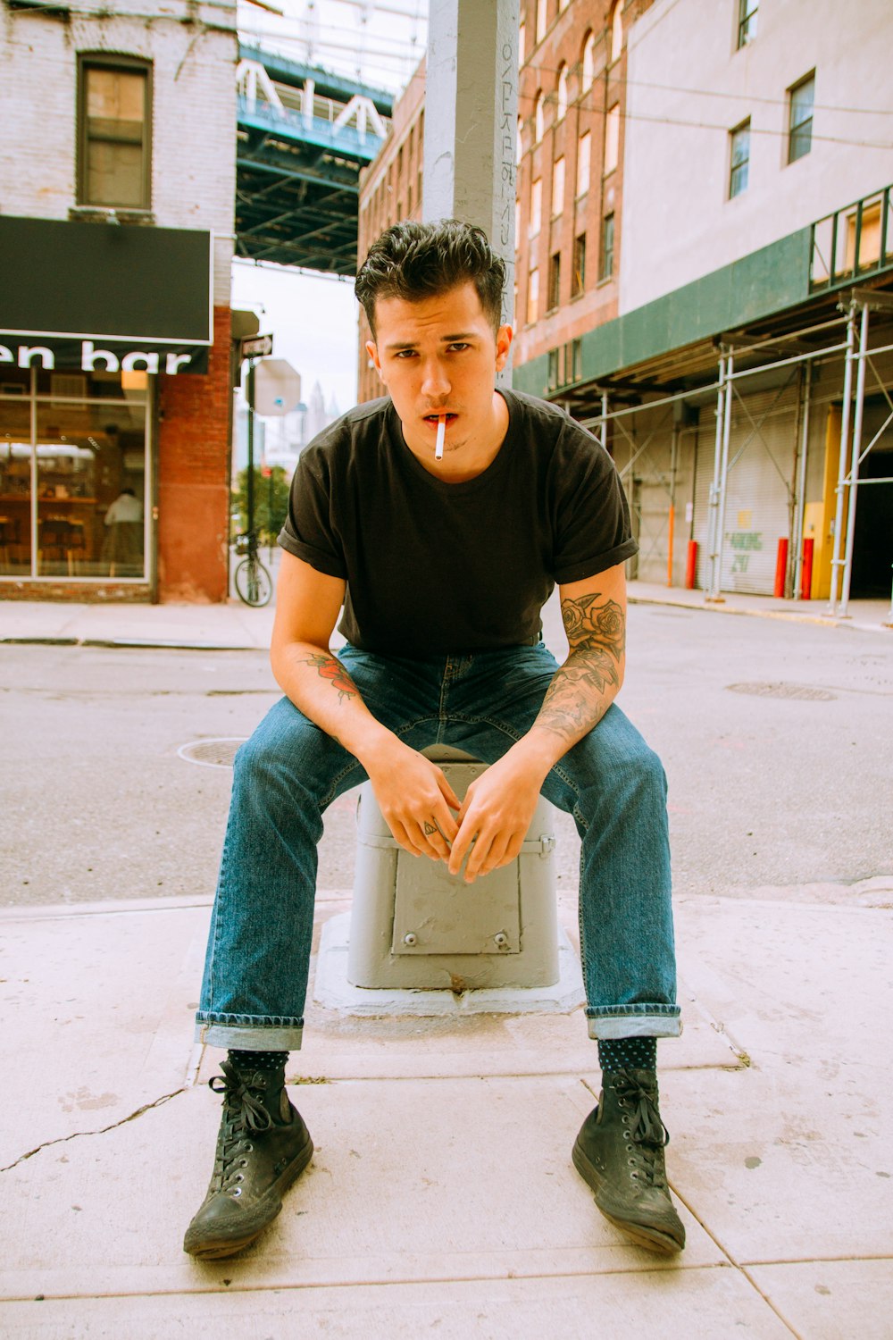 man in black crew neck t-shirt and blue denim jeans sitting on concrete bench during