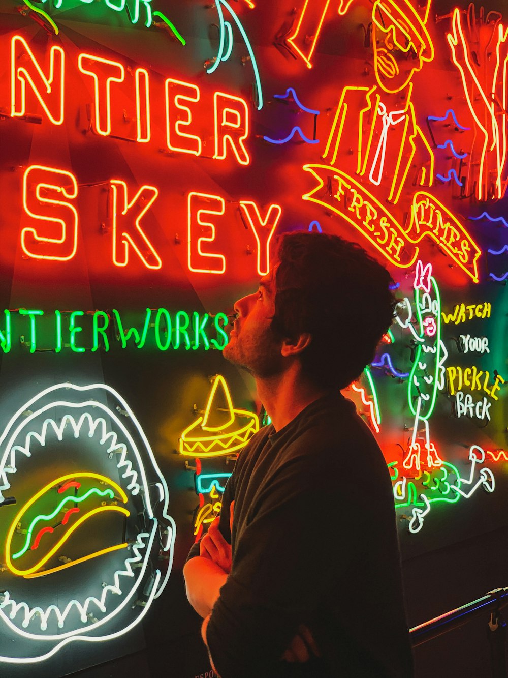 man in brown shirt standing in front of neon signage