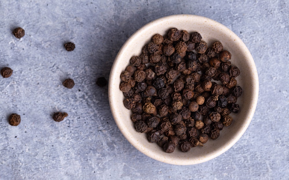 chicchi di caffè marroni su ciotola in ceramica bianca