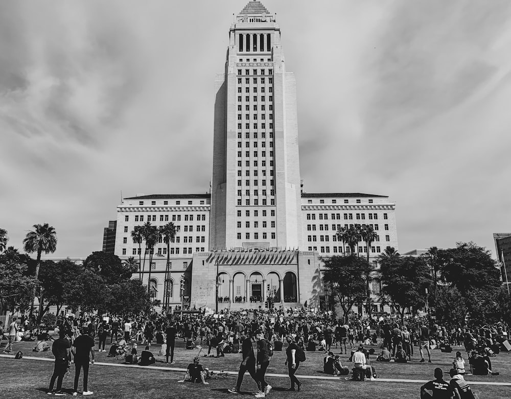 grayscale photo of people walking on street near building