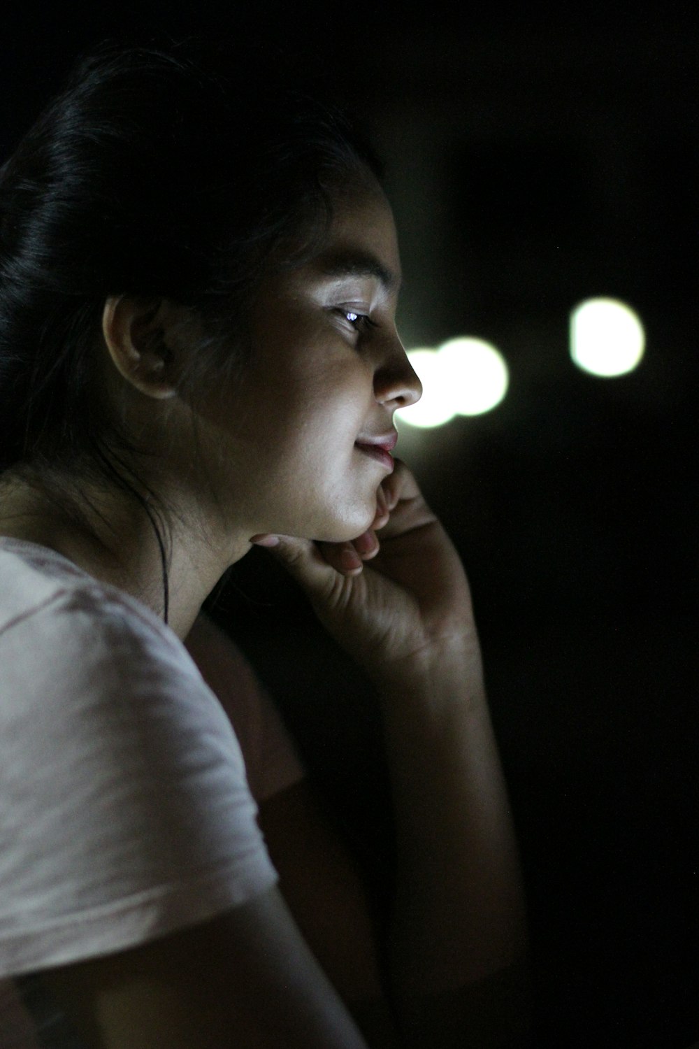 woman in white shirt with left hand on her face